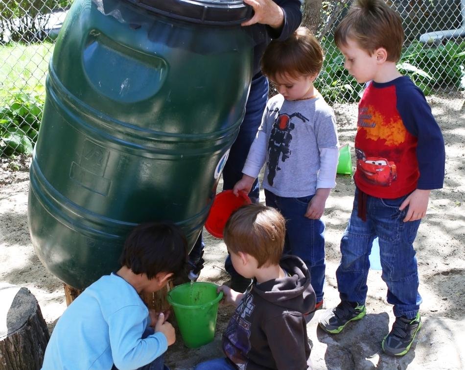 teacher helping kids with water barrel outside